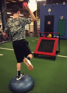 Trainer demonstrating plyometric throw on BOSU ball at Elite Sports Performance & Physical Therapy
