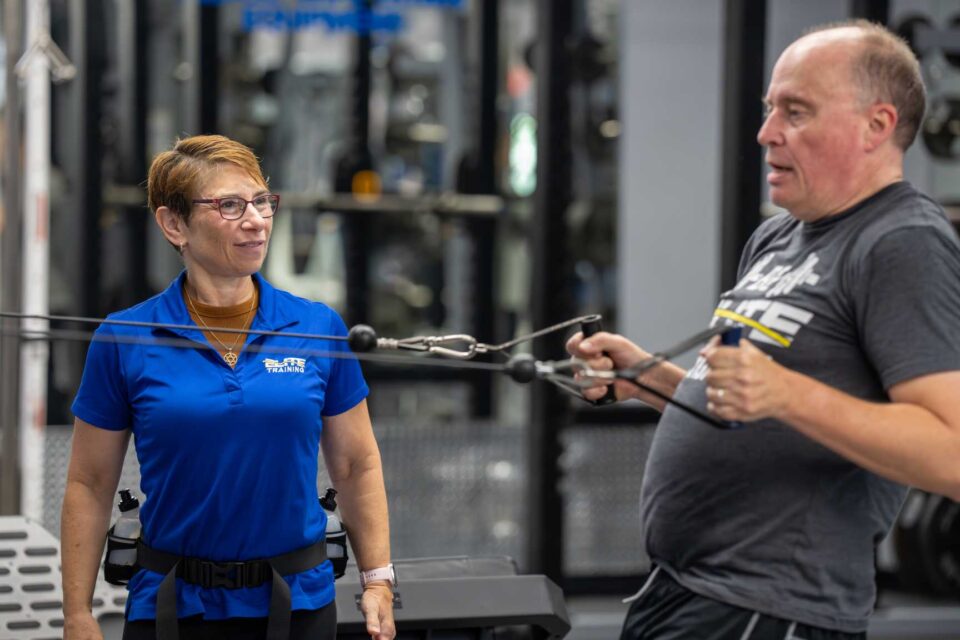 Trainer observing man using resistance bands in a gym in Foxboro, MA