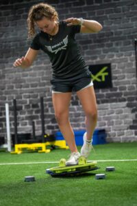 Woman balancing on a lime green roller board in Foxboro, MA