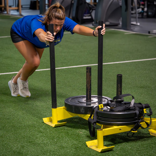 athlete pushing weighted sled on turf