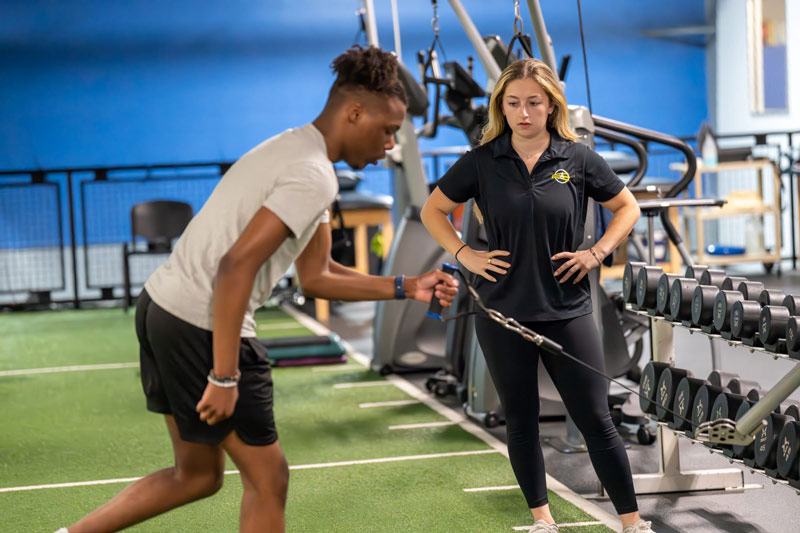 trainer guiding cable exercise in gym